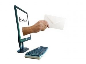 Desktop computer with hand emerging from screen holding envelope