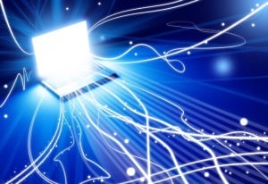 Illuminated laptop with streams of light representing online advertising reach